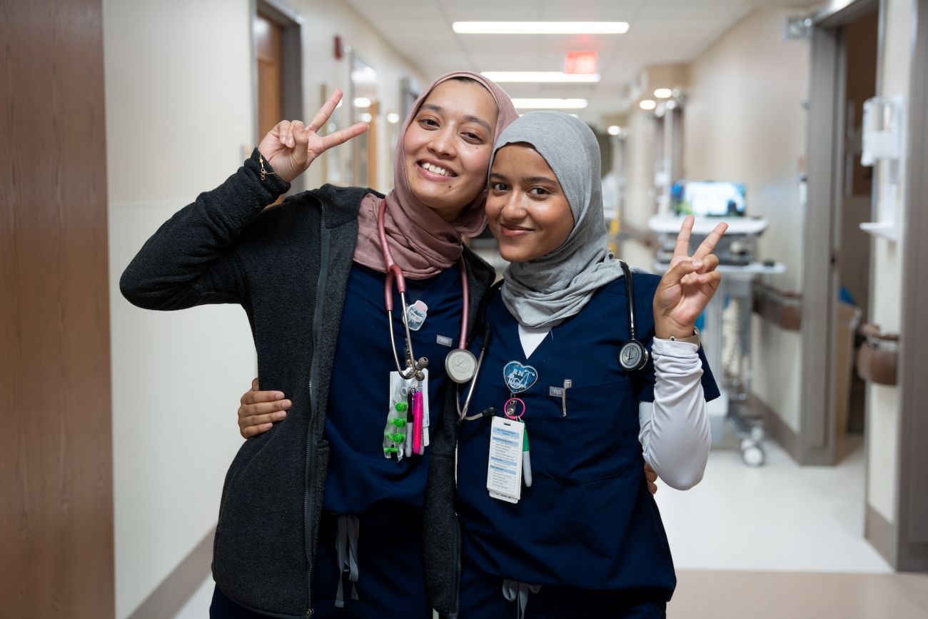 Two nurses poses in a hospital hallway