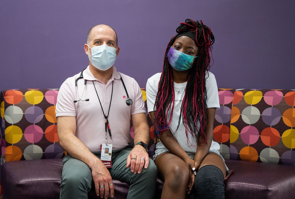 Dr. Steven Ambrusko and patient Jimeerah McKnight sit together in the pediatric oncology clinic