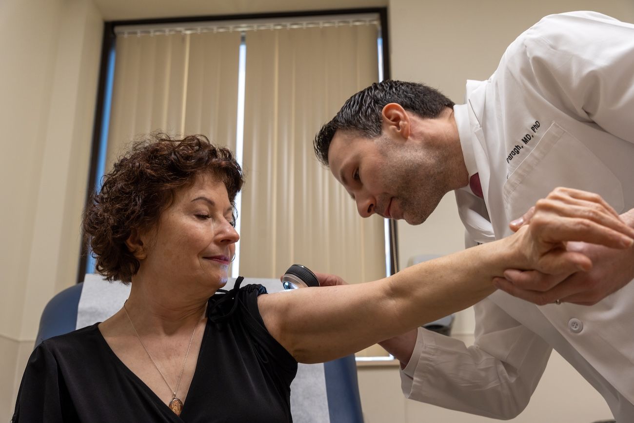 Dr. Gyorgy Paragh examines a patient's arm and shoulder in clinic 