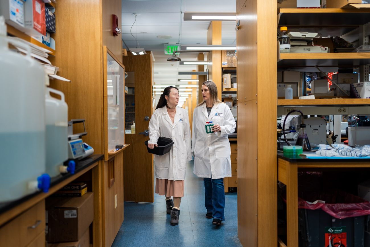 Researchers walk and talk in a lab.