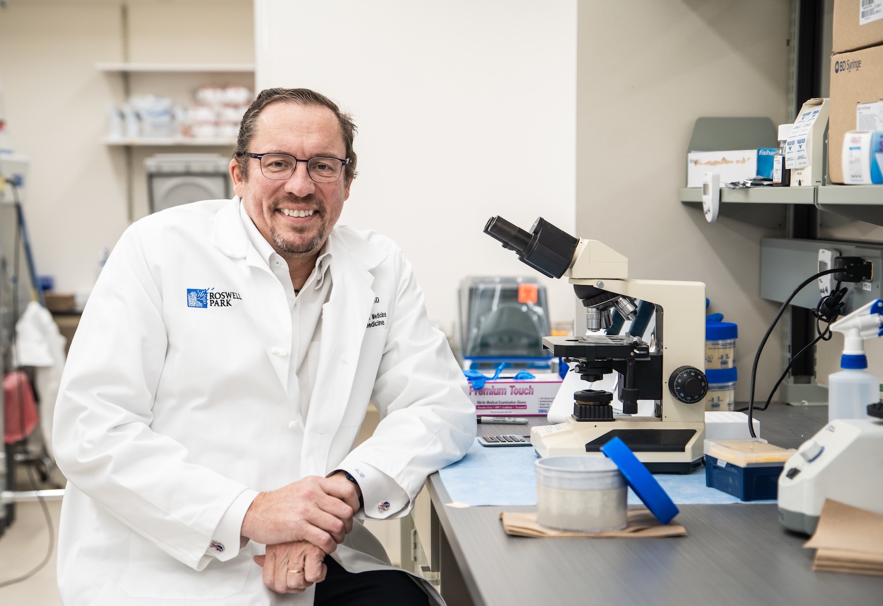 Dr. Brentjens in lab at microscope. -2023