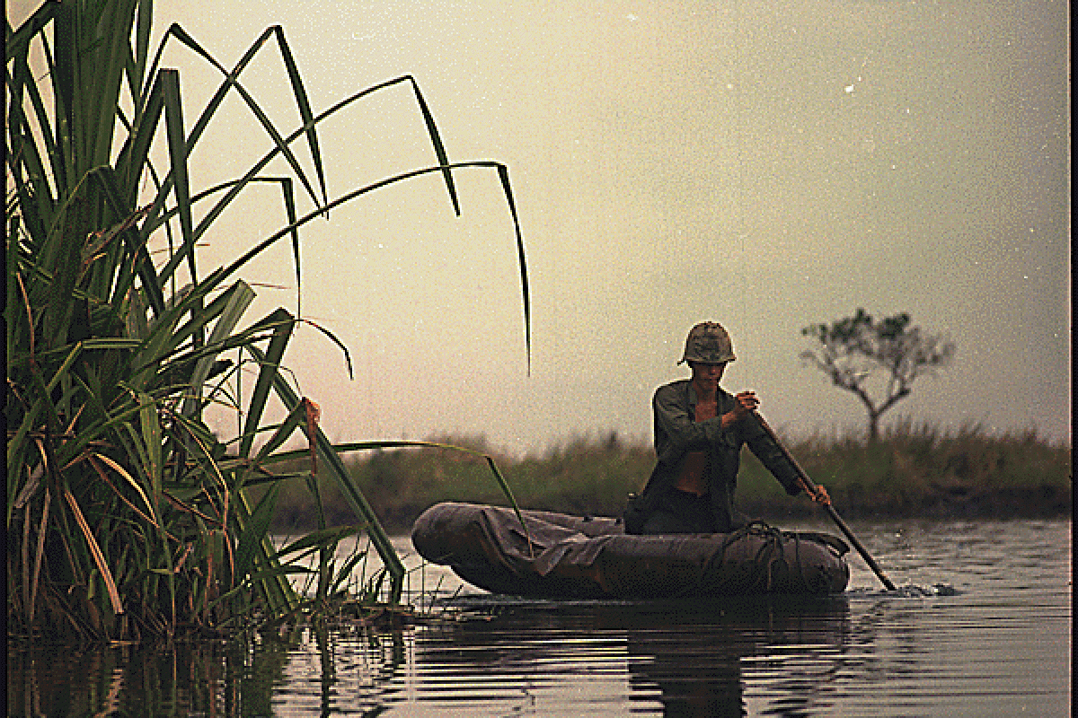 US Army private paddling in an inflatable boat in a river in Vietnam, 1968