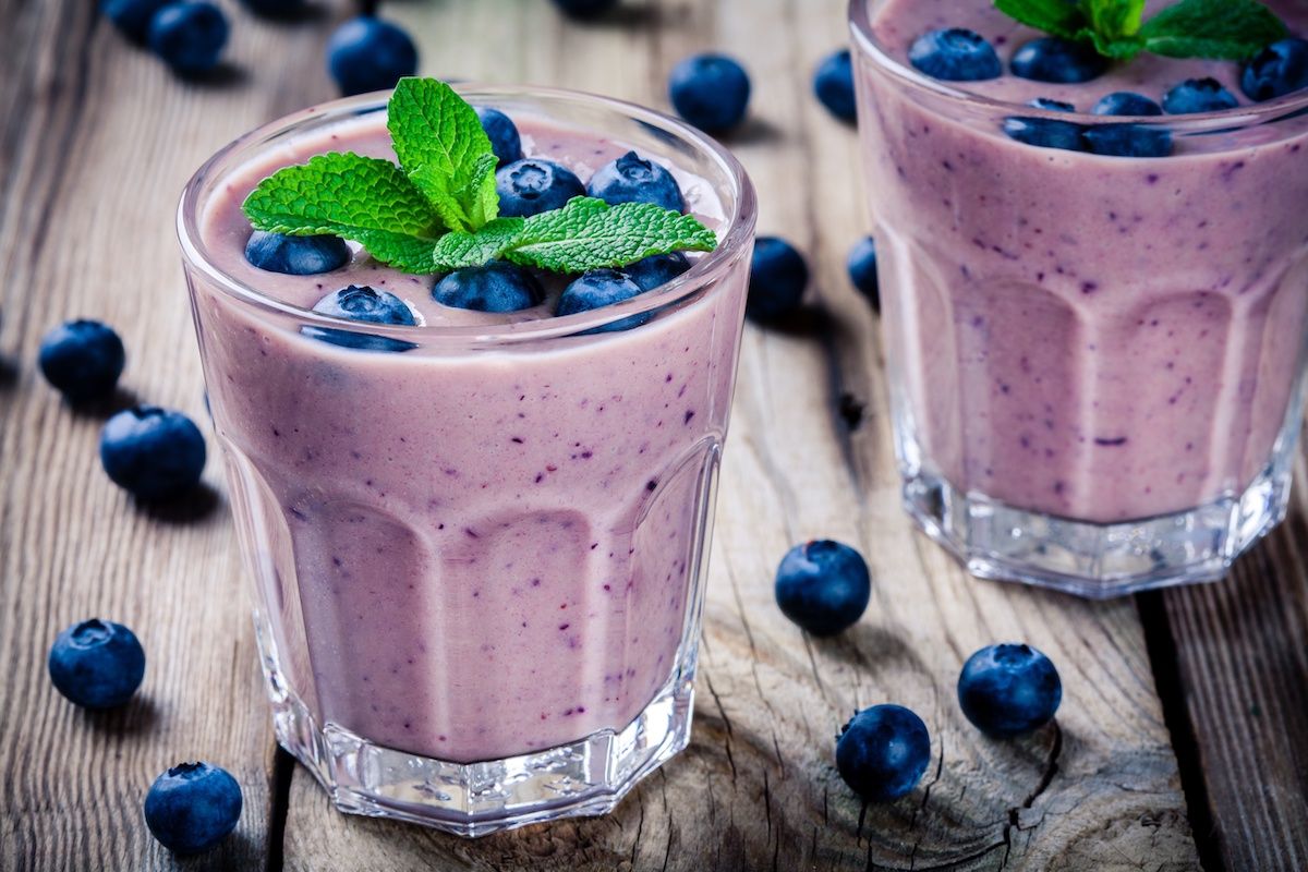 Two glasses filled with blueberry smoothies and garnished with mint