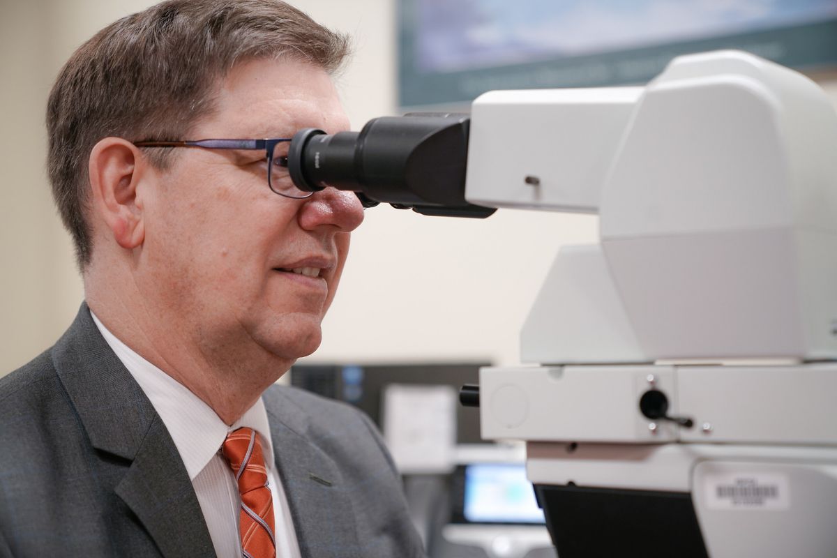 Dr. Charles Levea looking through a microscope to confirm a diagnosis.