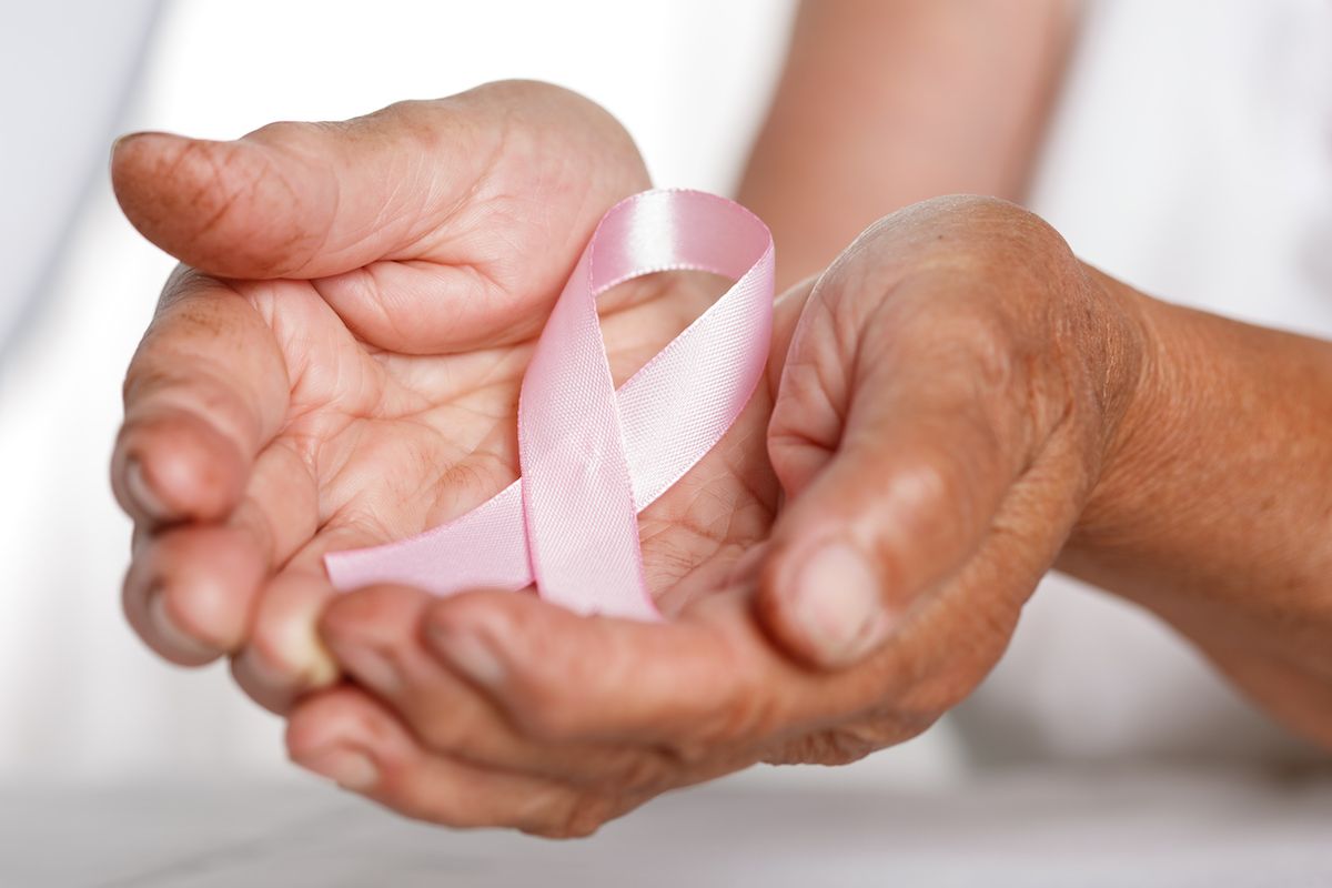 Woman's cupped hands holding pink cancer ribbon