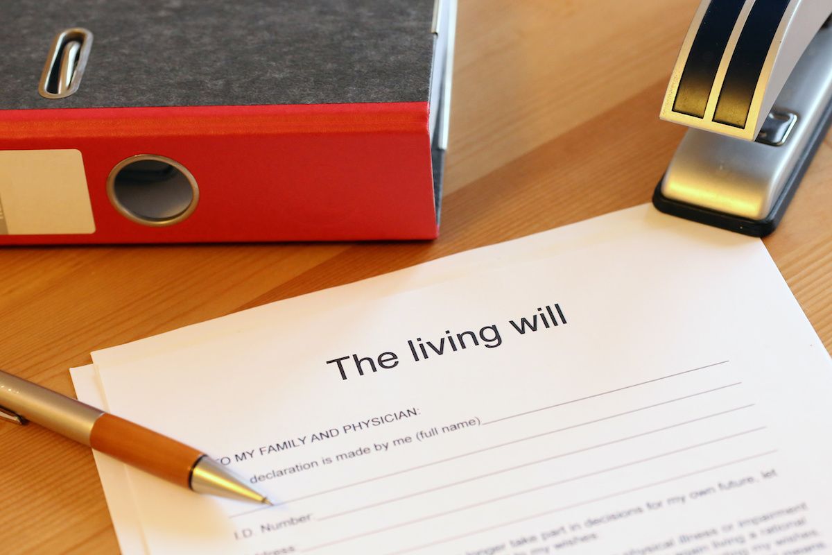 Document titled "The living will" on a table surrounded by a pen, stapler, and a binder