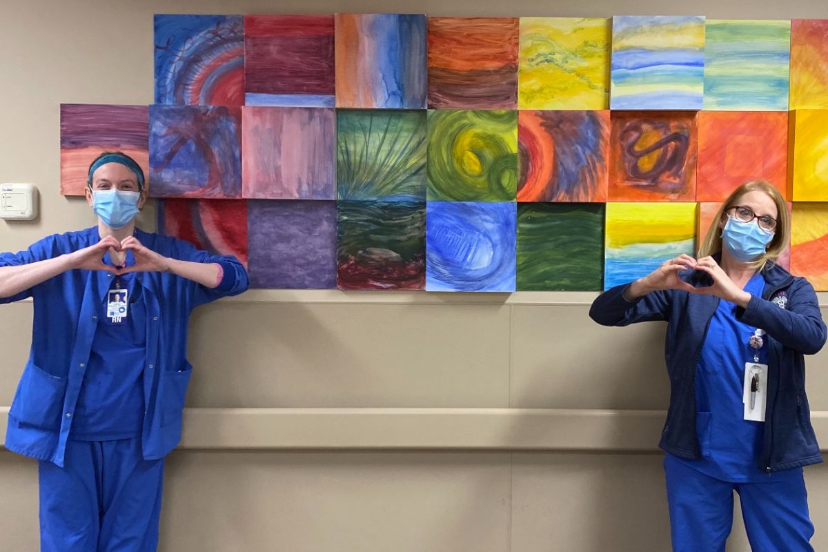 Two nurses in masks show heart hands