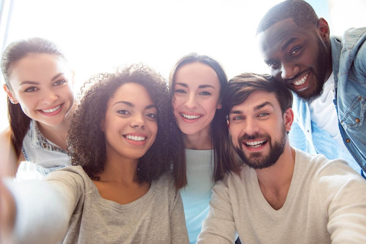 A group of young people, including three women and two men, smile at the camera.