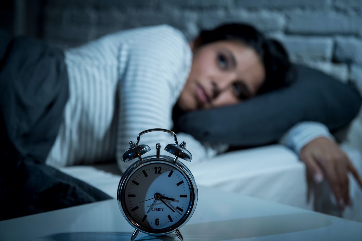 Woman awake in bed watching alarm clock