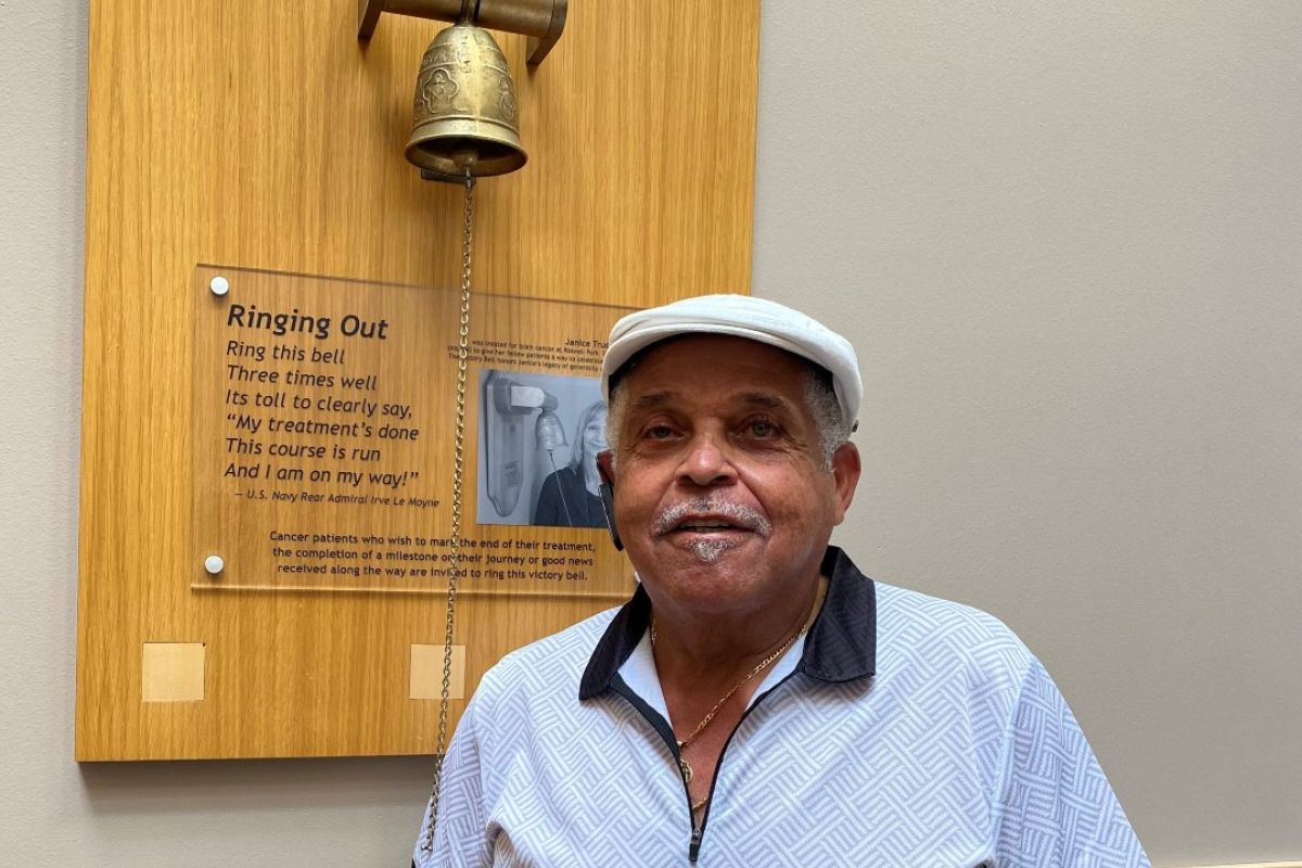 Rochester Davis, a prostate cancer survivor, stands next to the Victory Bell in the lobby of Roswell Park Comprehensive Cancer Center. 