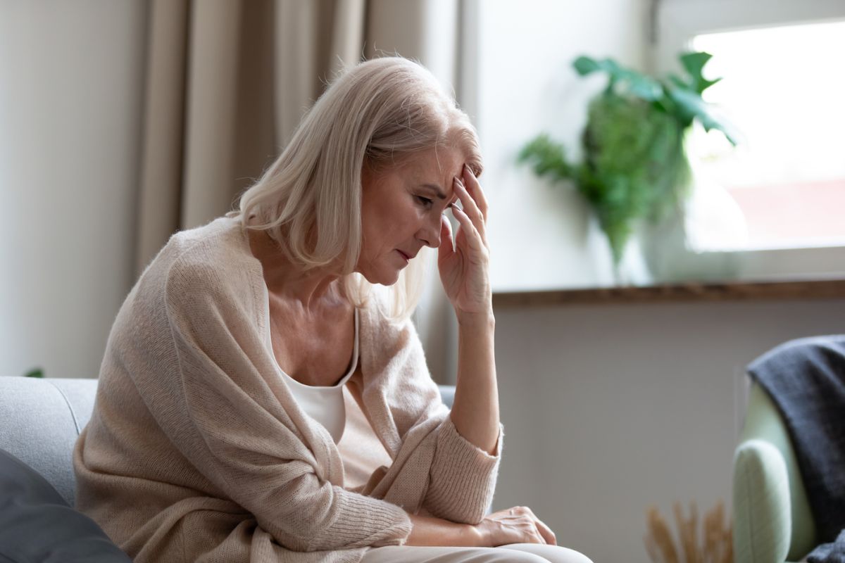 Woman sits with her hand on her head in anxiety - stock