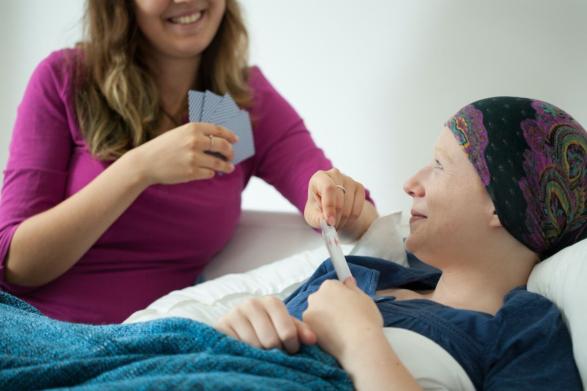 Photo of cancer patient and friend playing cards.