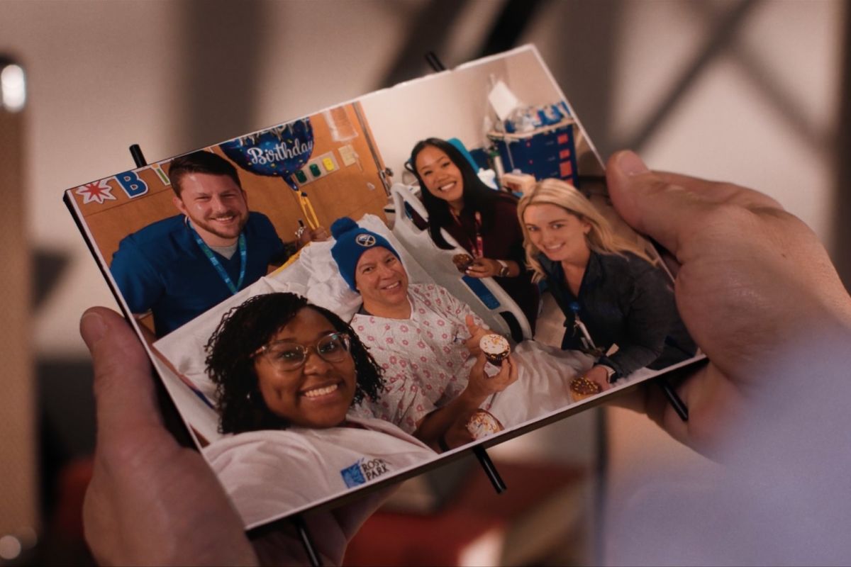 a person holds up a framed photograph of a patient in a hospital bed