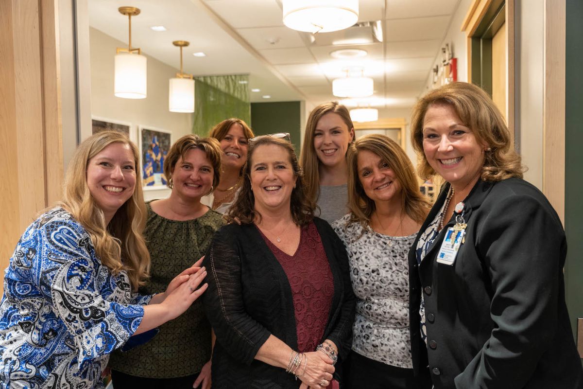 A group of women gather together, with big smiles, welcoming patients to the Resource Center.