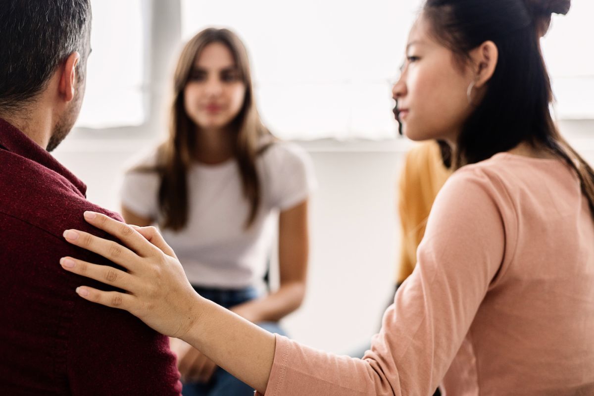 A group of young people sit together and comfort someone in their group