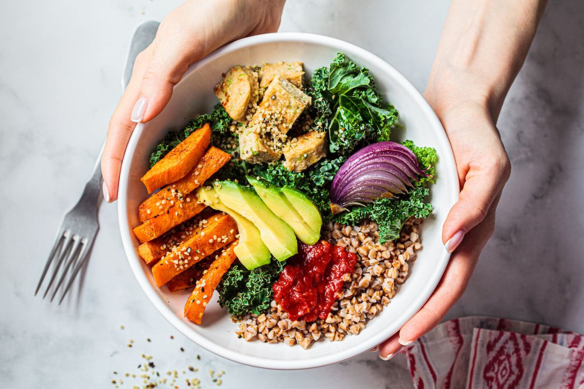 Hands holding a colorful bowl of salad