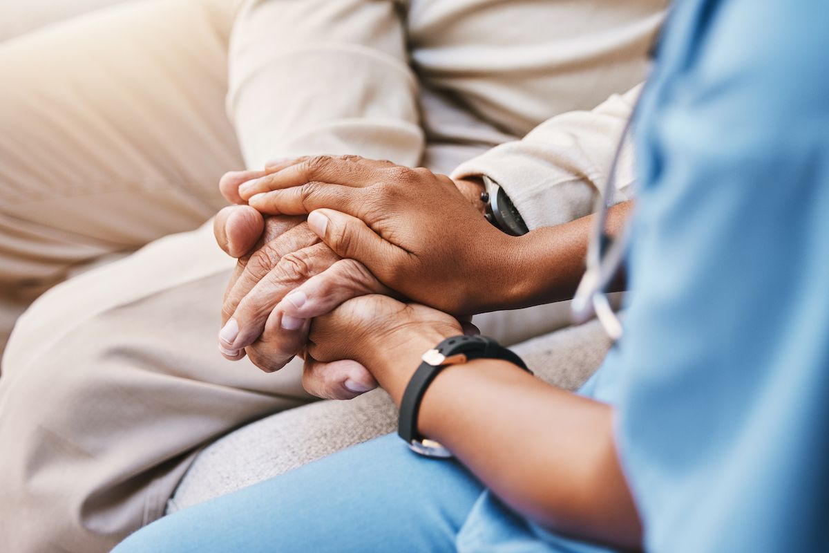 Physician holds hands with a patient