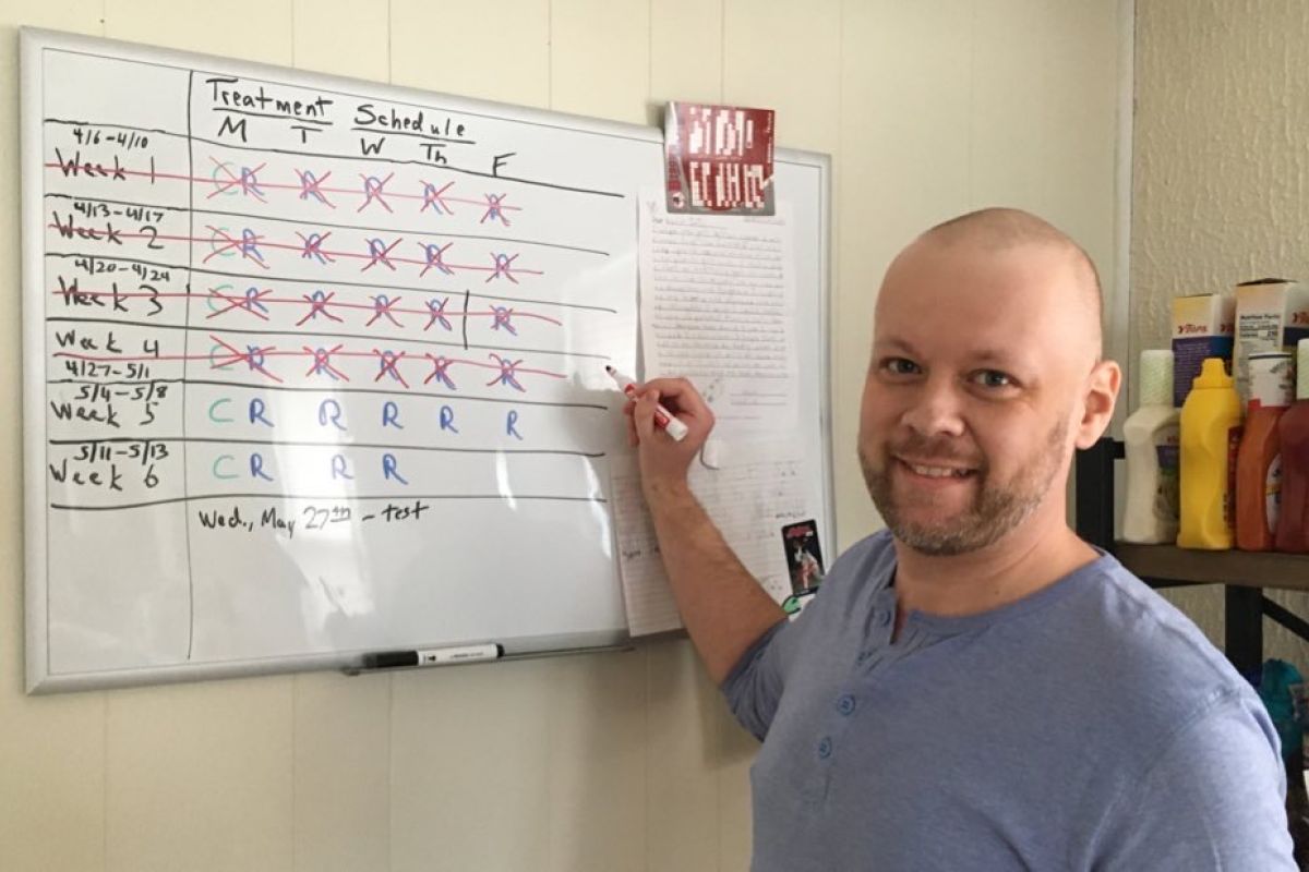 Photo of JT marking off completed treatments on his white board