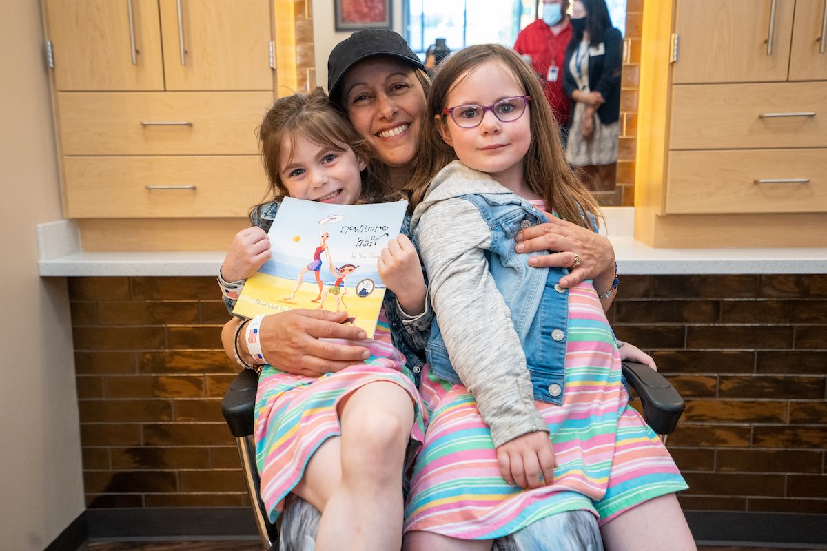 A patient sits with her two daughters at the grand opening of the Elevate Salon.