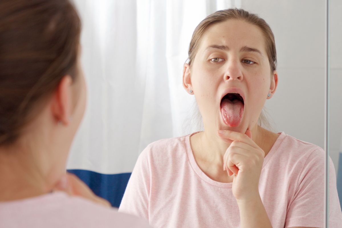 Woman looking at her tongue in the mirror