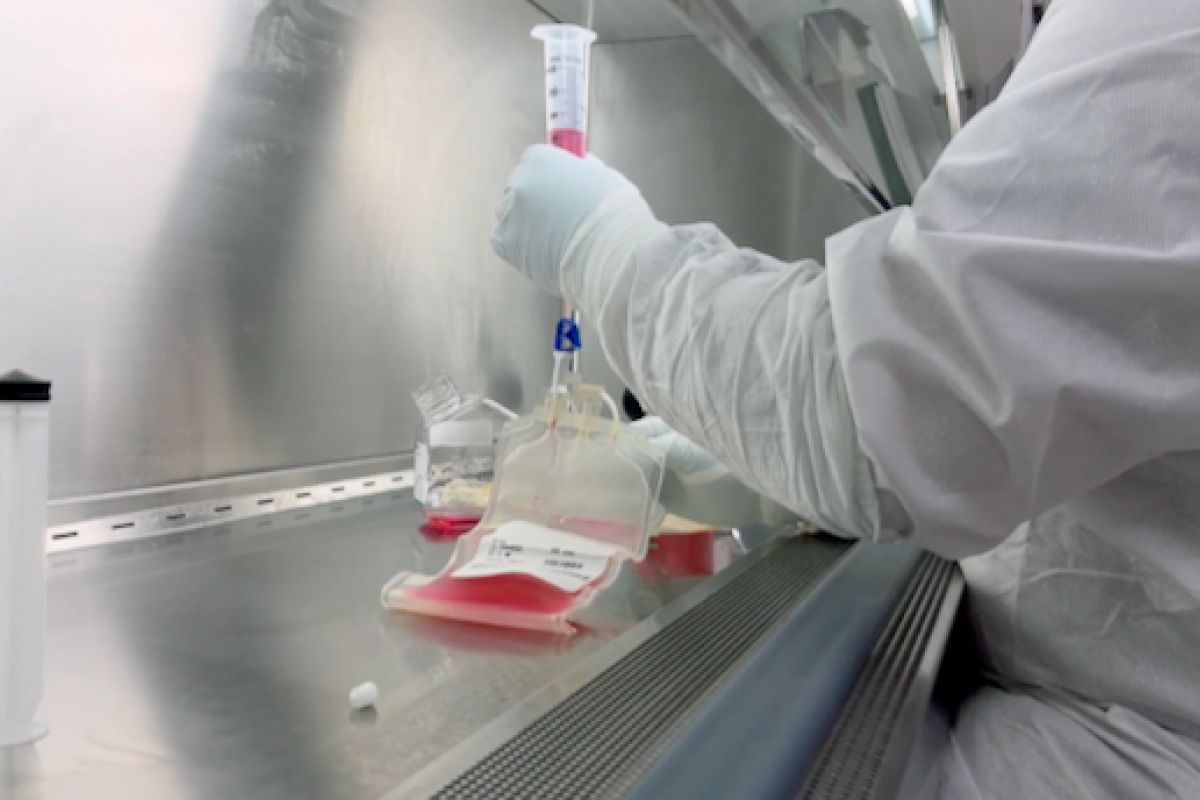 Tight shot of person's arm holding a tube of red liquid in a medical lab