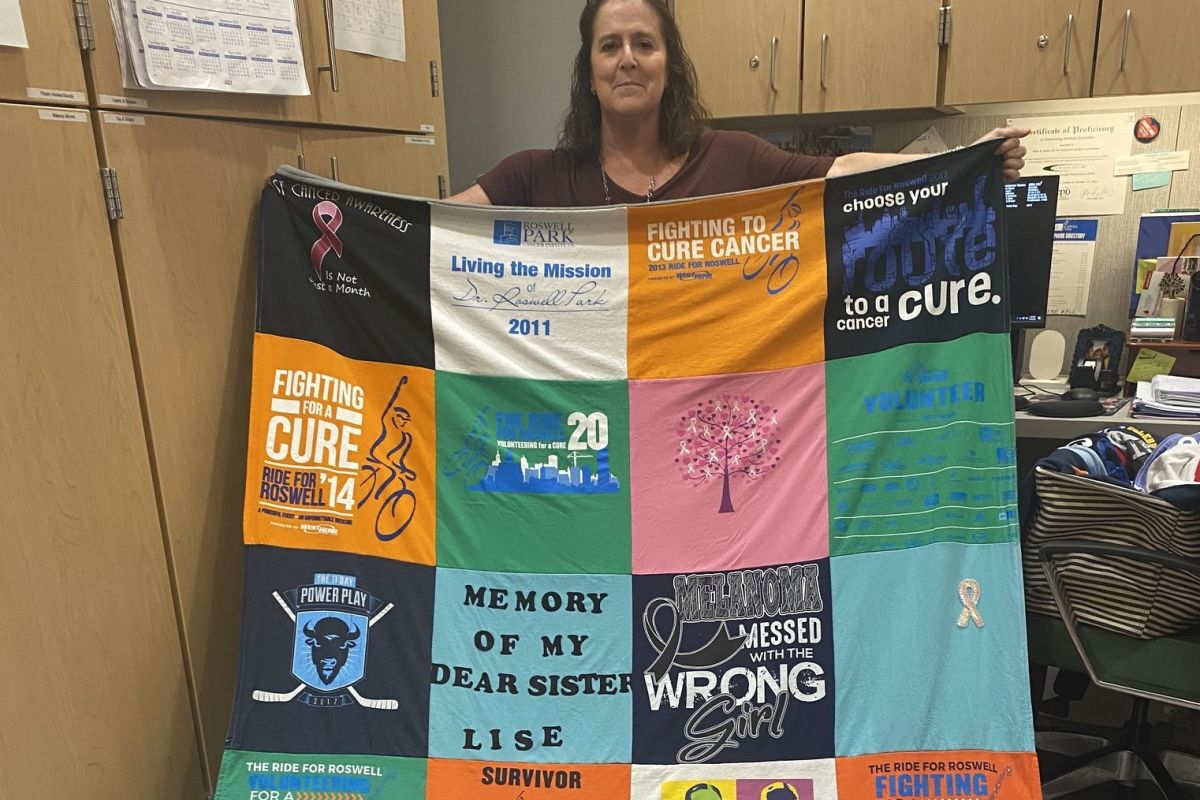 Woman holding a quilt she made from old t-shirts