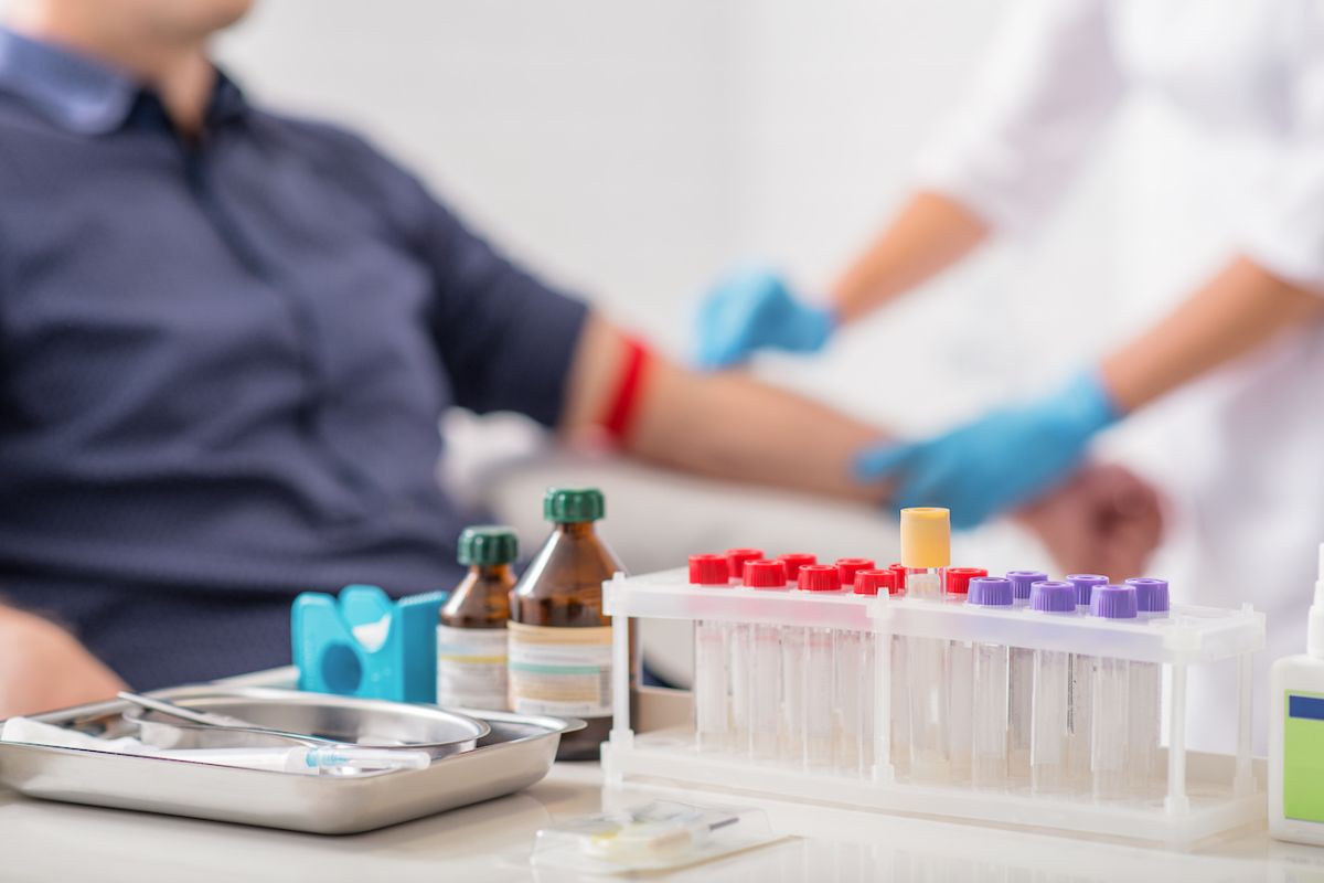 Test tubes on a table while a person gets prepped for a blood test