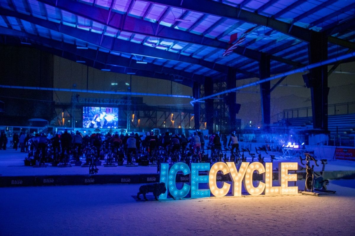Wide shot of people riding a stationary bike on ice
