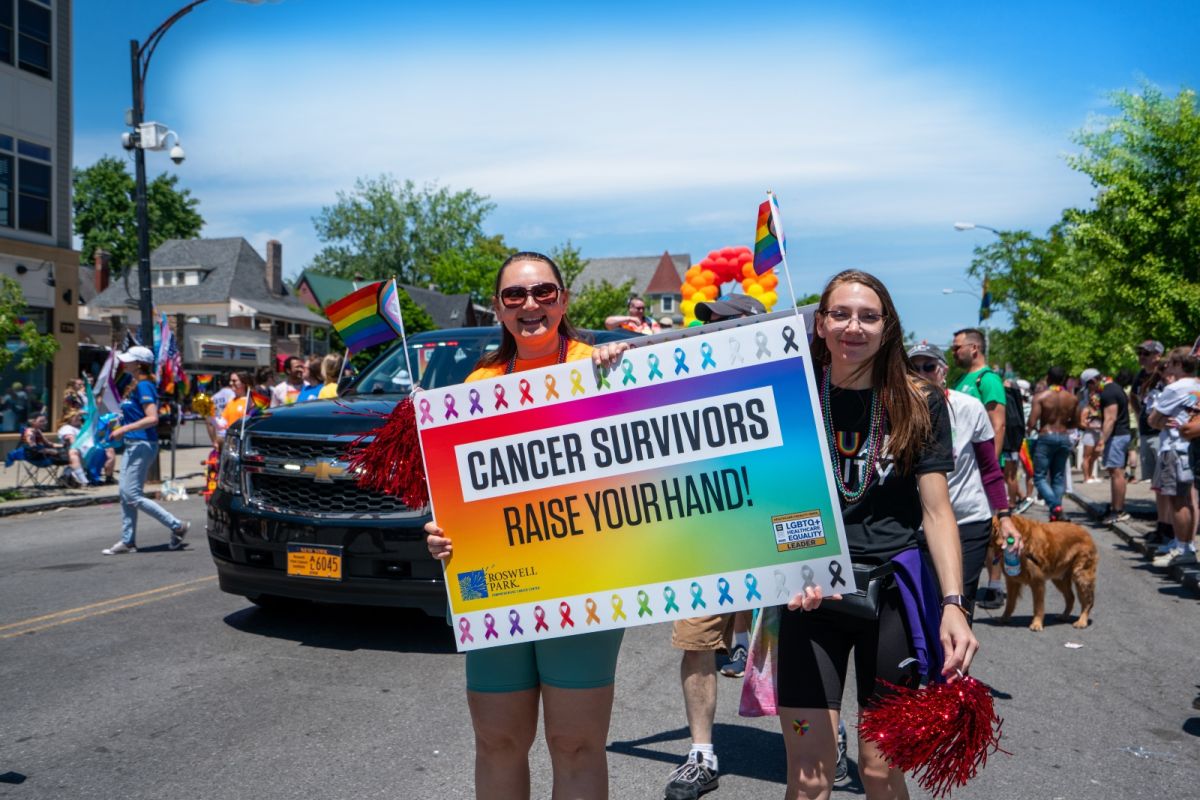 two women hold up a rainbow colored poster at pride