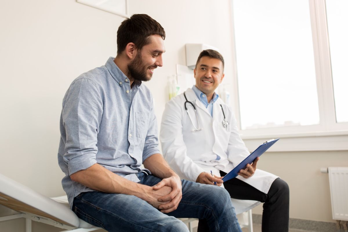 A young man sits with his doctor in an exam room