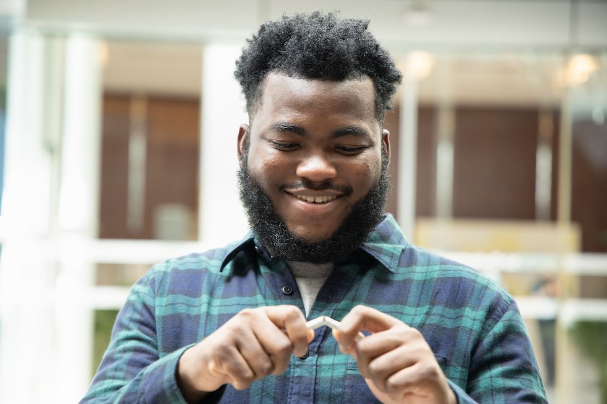 Black man breaking cigarette in half