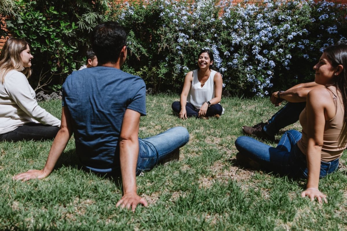 Six young people sit in a circle having a conversation and supporting each other
