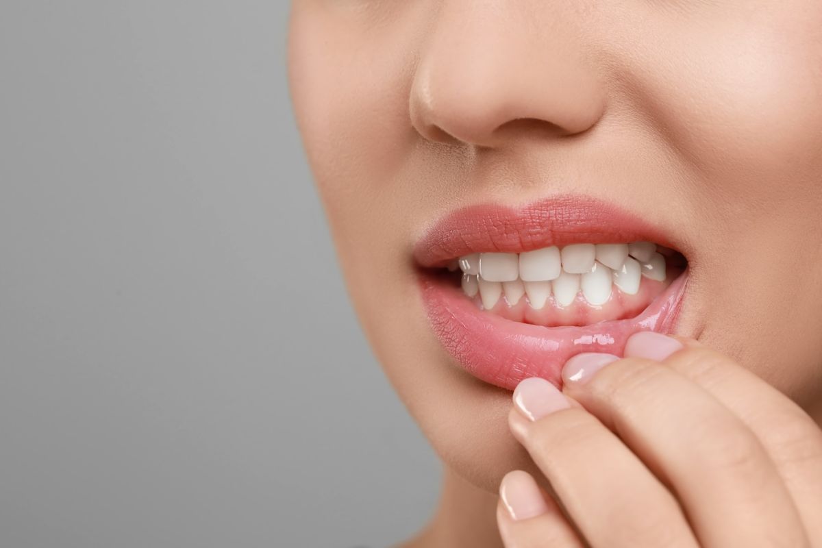 Woman holdings her mouth in pain, revealing a red and swollen gum line