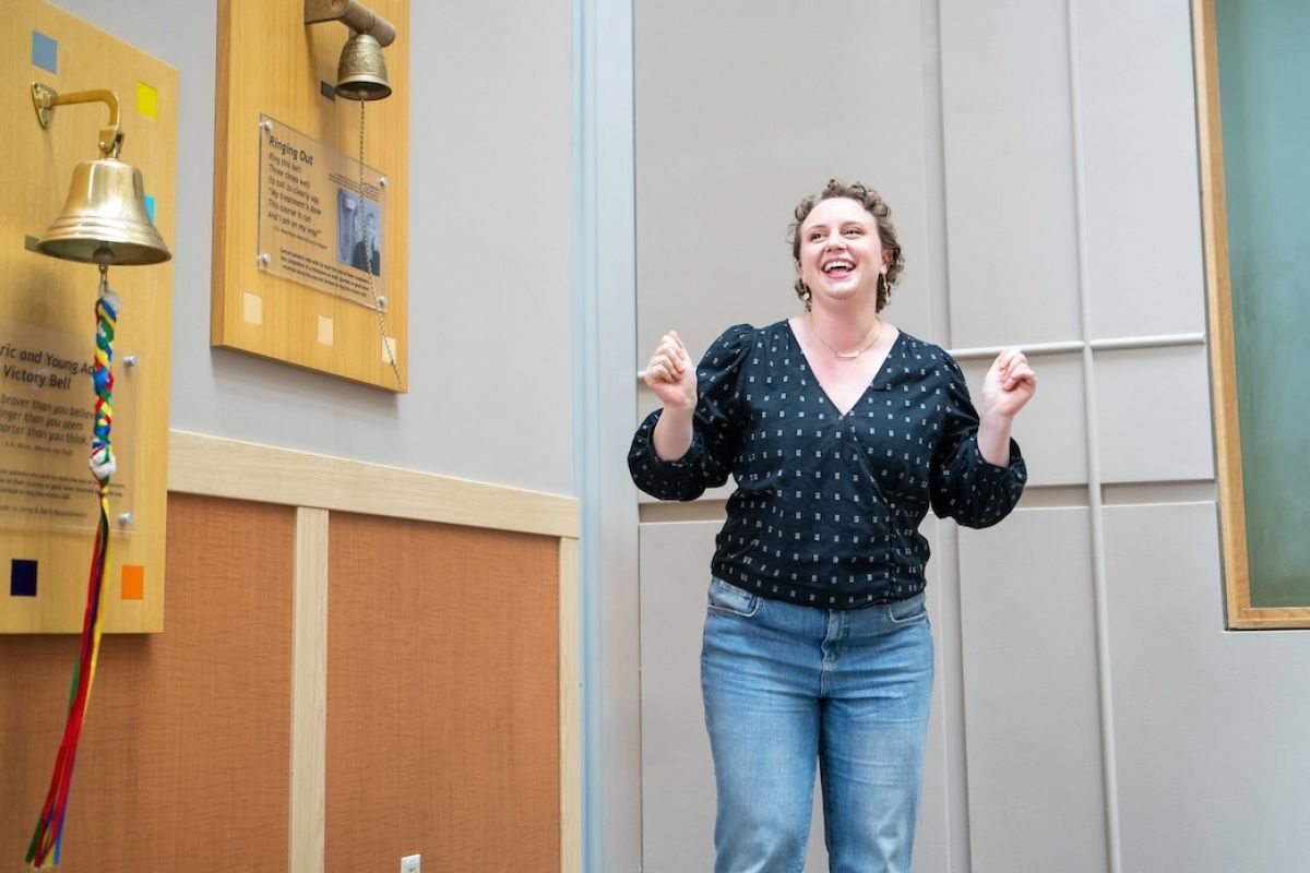 Hannah, a breast cancer patient and survivor, celebrates after ringing the Victory Bell