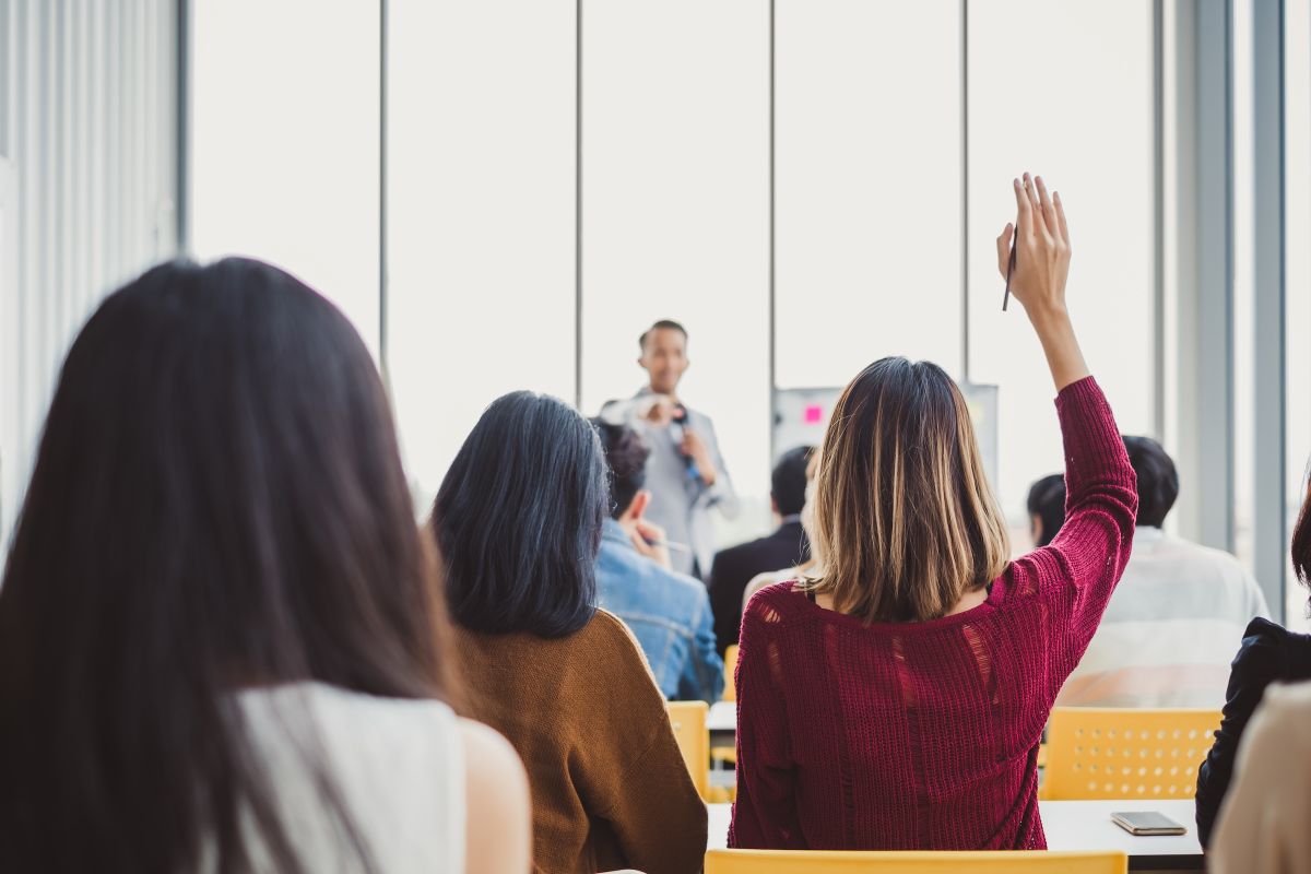 Woman raising her hand in a crowded room