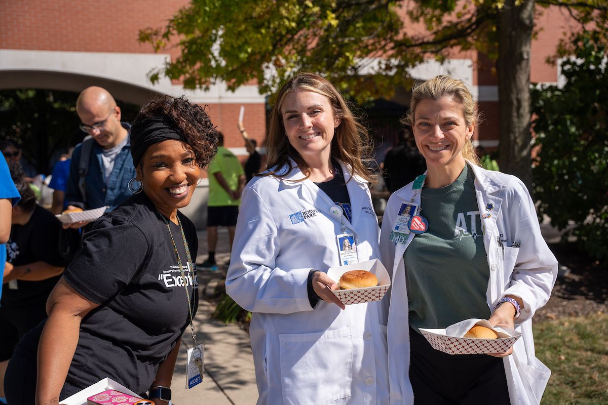 Three employees pose outside 