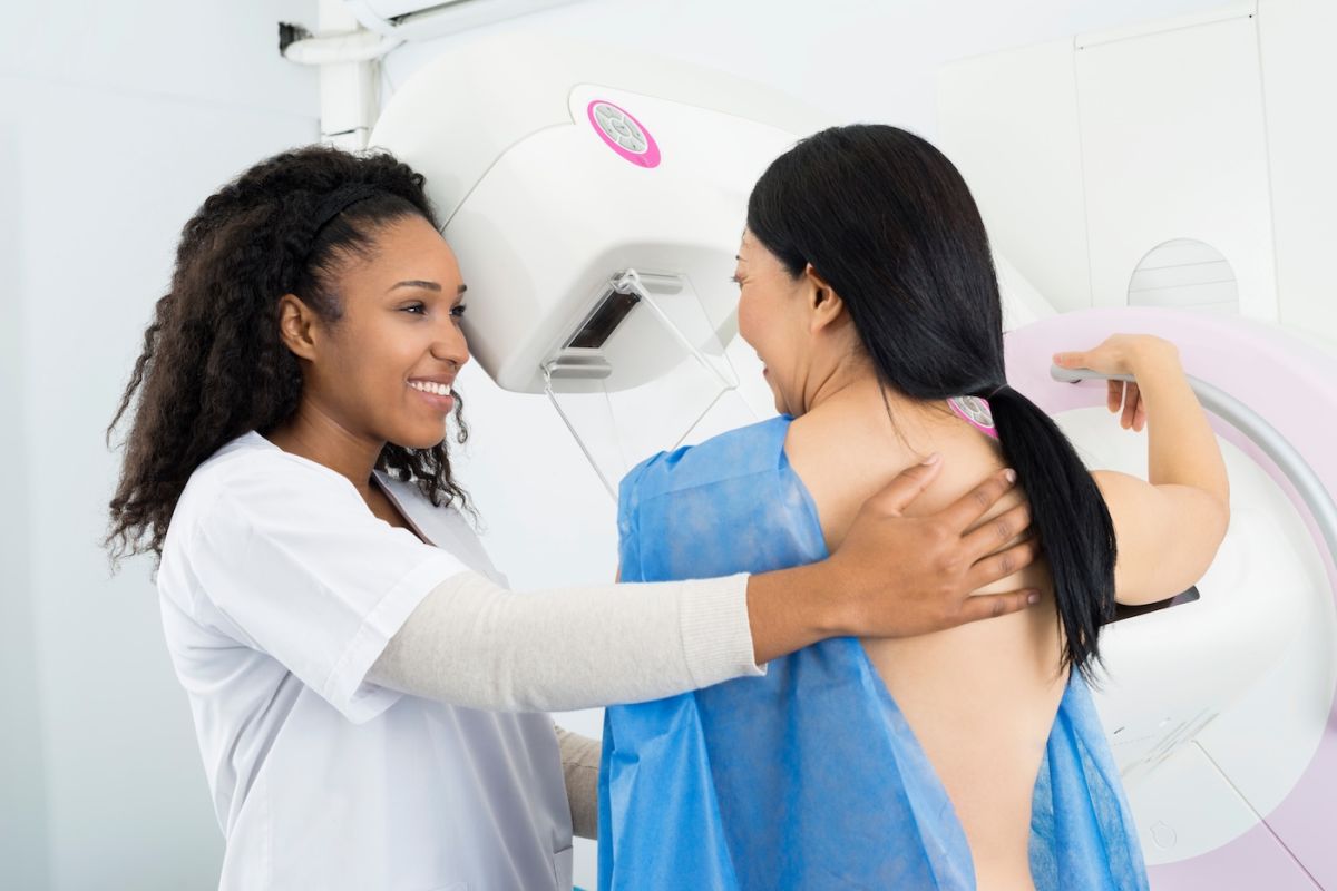 A female doctor assists a patient before they receive a mammogram