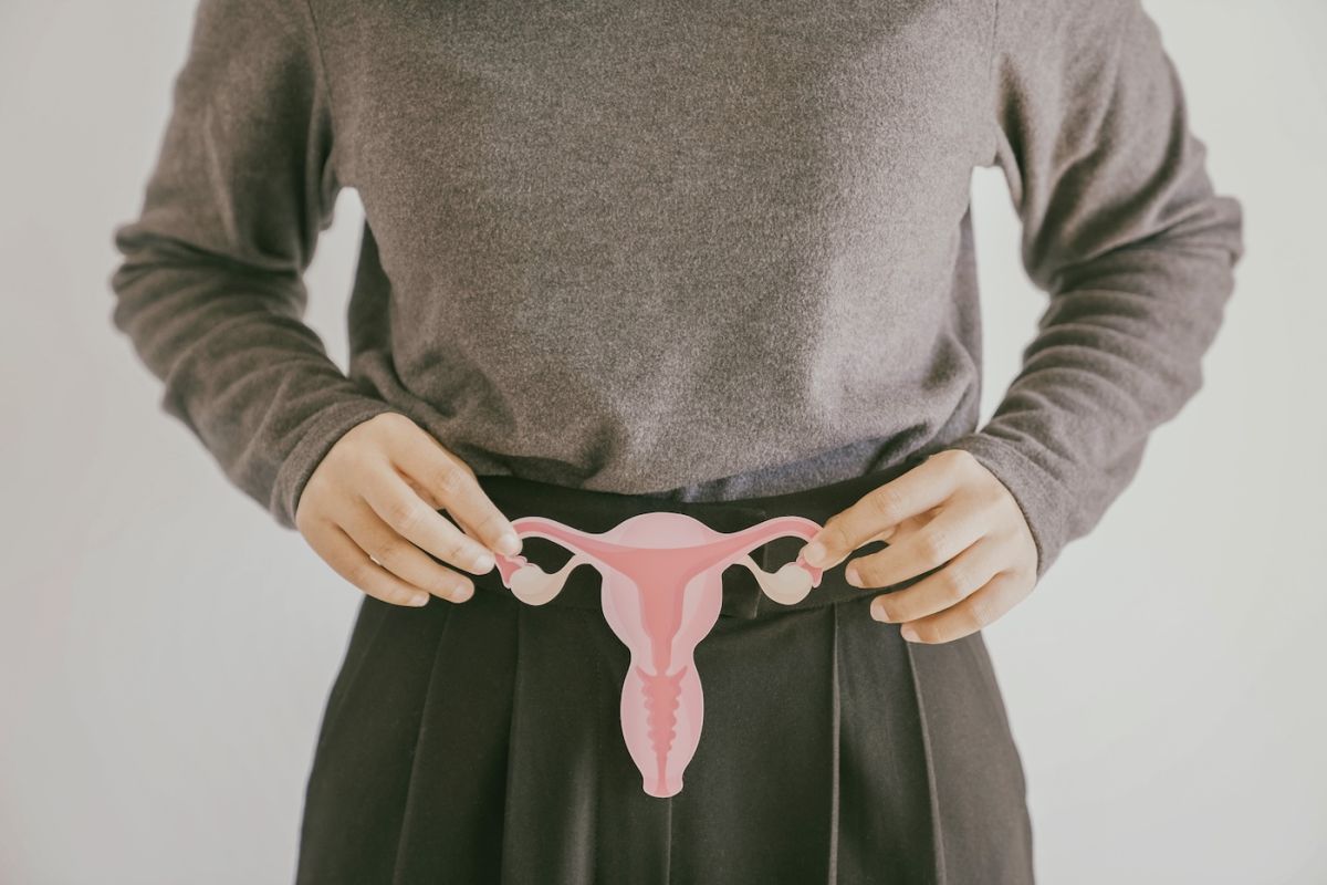 A woman holds a diagram of a uterus and ovaries