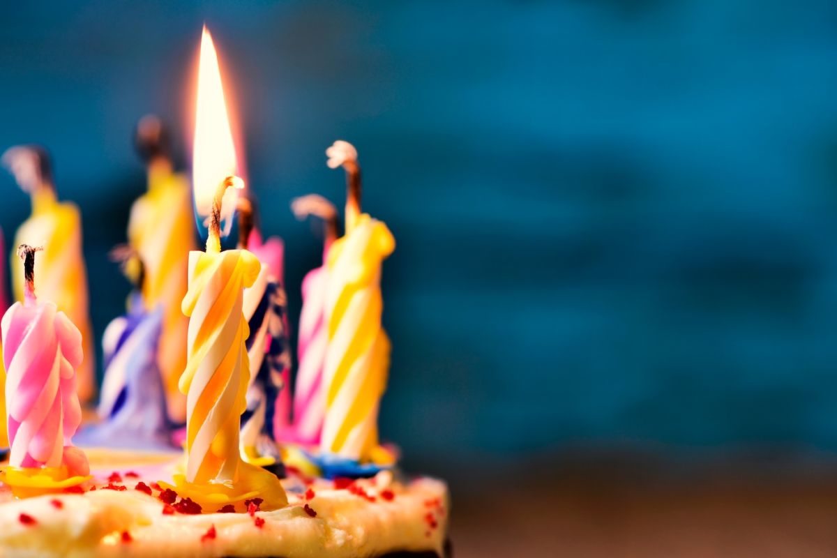 A birthday cake with a candle lit and the rest blown out