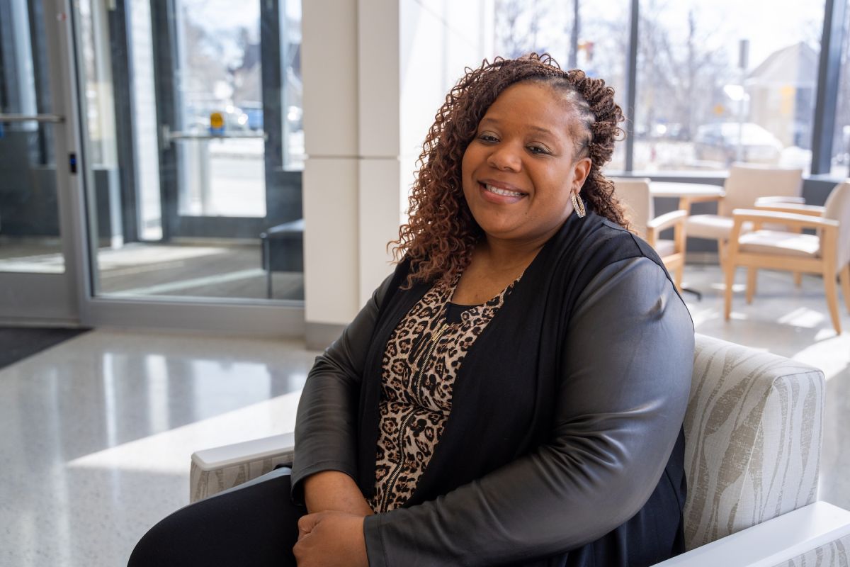 A woman sitting inside the sunny lobby of a building