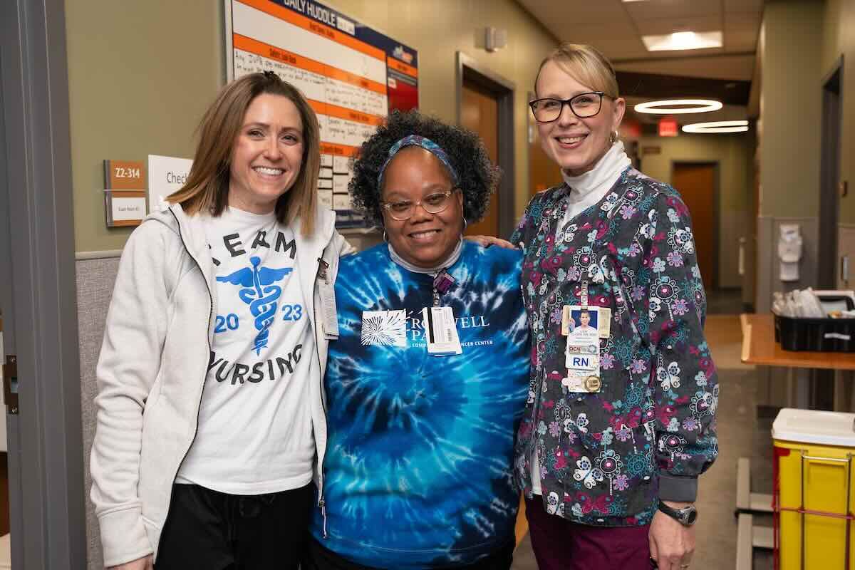 Three nurses stand in hospital hallway