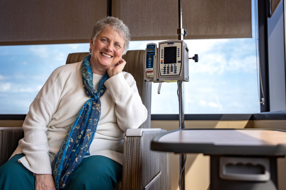 A woman sits in a chair receiving an IV