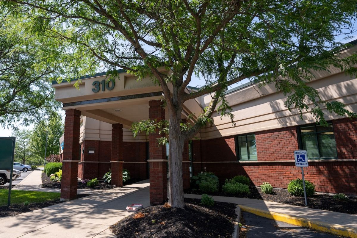 The exterior of a doctor's office underneath some shady trees.