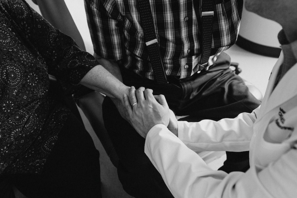 Dr. Dhir holds hands with a patient and his wife
