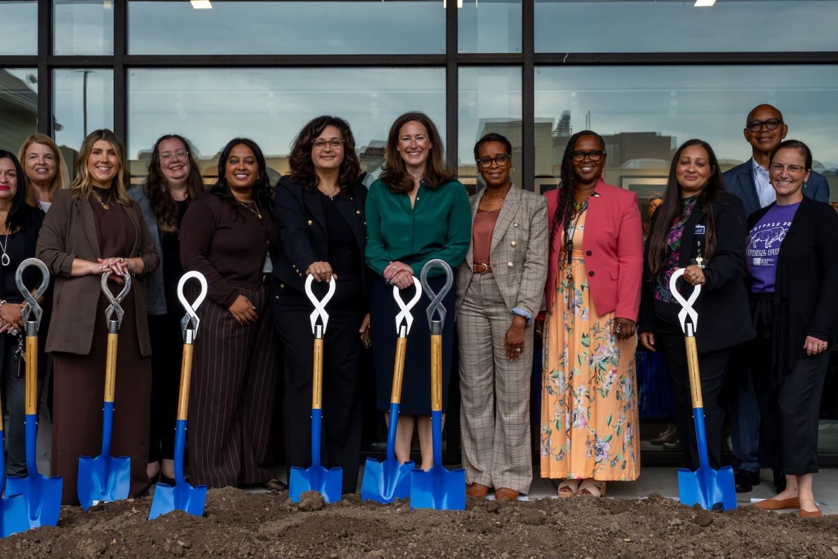 A group of people stand behind shovels at a groundbreaking