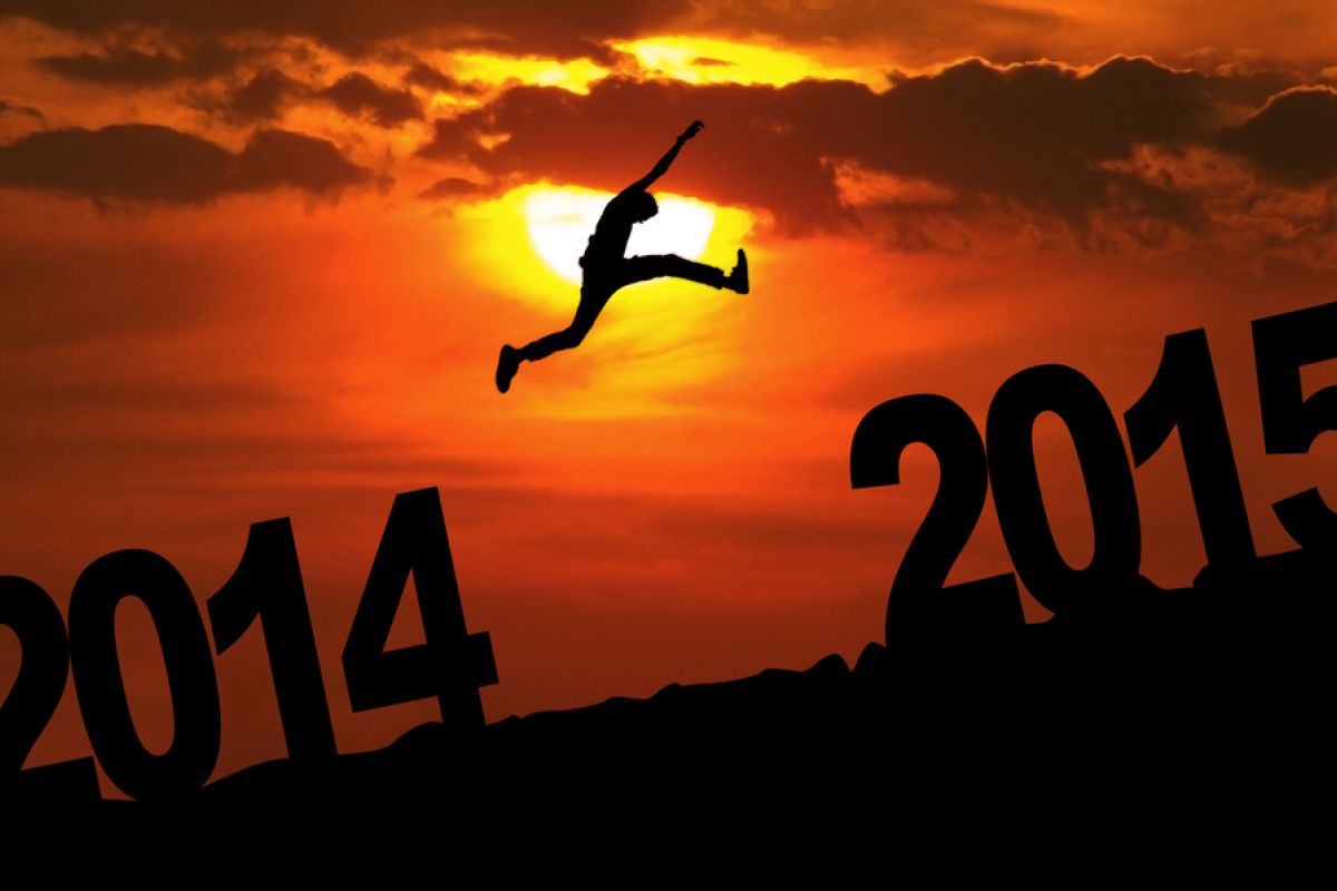 Person jumping from the number 2014 to the number 2015 in front of a sunset