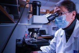 Researcher in Dr. Goodrich's lab using a microscope