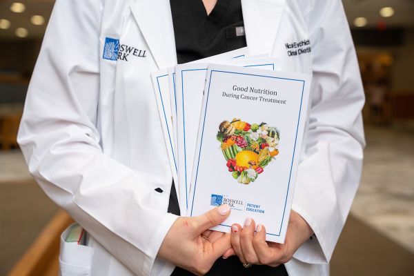 A nutritionist holding up a pamphlet of nutrition tips during cancer treatment 
