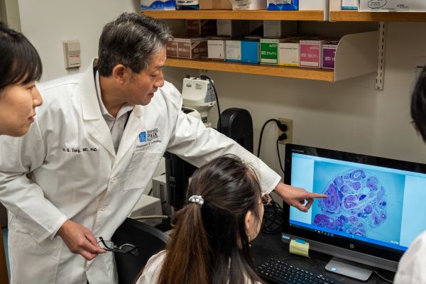 A doctor examines a cell slide with lab members