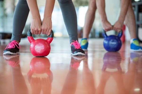2 people lifting kettlebells in an exercise class